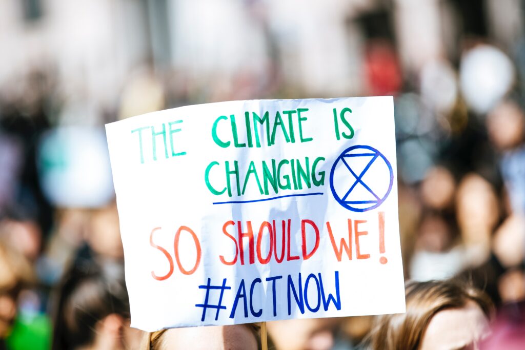 Sign at a protest that says "the climate is changing, so should we! #ActNow"